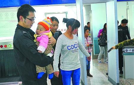 重慶江北機(jī)場(chǎng)安檢門(mén)通道工作員抱小孩兒助乘客安檢[圖]